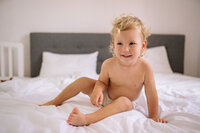 Jeune enfant en couche culotte souriant sur un lit