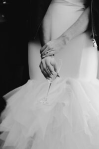 Black and white detail shot of brides hands with ring and drink flute