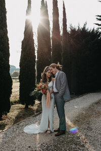 modern 70s styled bride and groom on driveway with sun