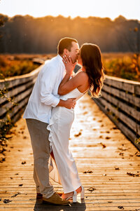 Engagement session on a bridge at sunset as a couple kisses
