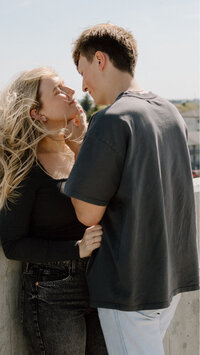 A man gently holding the neck of his girlfriend as he is about to kiss her.