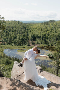 A person dipping their partner and kissing them on a hiking trail