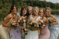 bride posing with her bridesmaids who are all wearing different color dresses