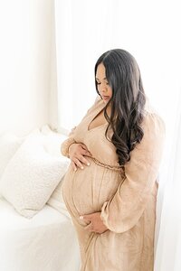 pregnant mother wearing peach dress poses during maternity photo shoot in Louisville Ky with Julie Brock Photography