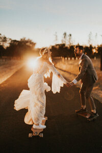 wedding couple skateboarding into the sunset