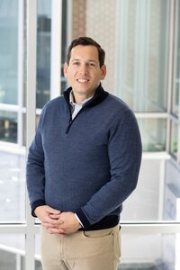 Businessman in a sweater in conference room with lots of glass behind him