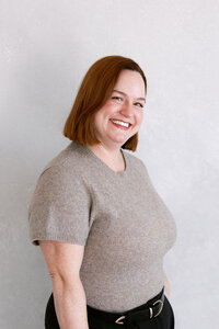 Anna Delores Photography photographer, Brett, smiles in tan sweater and black pants