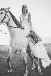 Black and white elegant bride riding a white horse