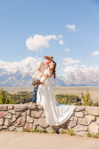 Bride and groom sharing a romantic kiss while eloping at the breathtaking Snake River Overlook in Jackson, Wyoming, with the majestic Teton Mountains as their stunning backdrop.