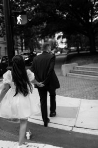 A bride and groom walking hand-in-hand in an urban setting, possibly in NYC, showcasing Hallie’s ability to blend romance with cityscapes.