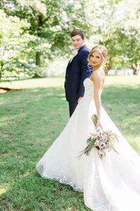 A bride and groom walk casually across the lawn after their first look on their wedding day