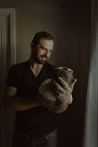 A dad holds his first baby in his arms.