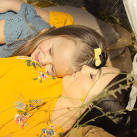 Mother and daughter snuggling with eyes closed in a field.