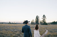 Bride and groom walking down a path at Grand Teton National Park during sunset.