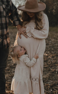 Dad with hand on pregnant mom next to toddler