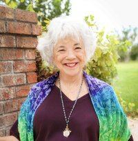 Client samarah headshot smiling at camera wearing purple blouse and rainbow scarf