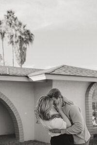 black and white photo of a husband and wife in front of a home