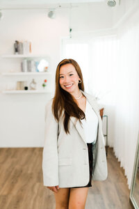 Coastical Designs, a luxury branding and custom website design expert, standing next to windows with an iPad, showcasing her professional approach to creative branding solutions and custom web design services.