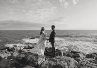 A couple eloping at Otter Point in Acadia at sunset holding hands.