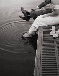 Bride and groom sitting on a dock with their feet in the water, captured by a Washington elopement photographer.