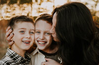 A mother hugging her two boys while kissing one of their cheeks in Fort Worth, Texas