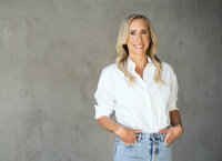 Nicole Woods wearing a white shirt and jeans in front a textured backdrop