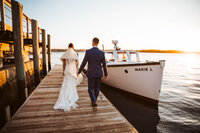 A couple at sunset walking down a dock overlooking the ocean.