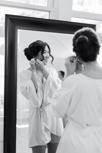 A person looking in a mirror as they put on an earring 