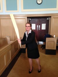 Patty holding an object like a baseball bat in a courtroom
