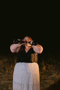 woman drinking from two bottles of champagne 