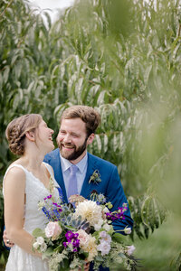 bride and groom laughing in an orchard