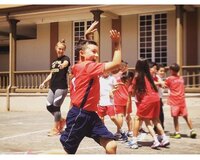 Kids run laughing while a photographer is laughing in the background helping the kids win a game.