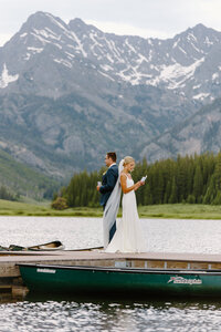 Wedding couple at Piney River Ranch sharing private vows at an alpine lake with the Colorado Gore Range mountains in the background