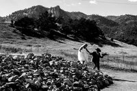 Bride wearing a white cowboy hat smiling during golden hour with Colorado mountain views in the background at her Colorado Springs wedding.