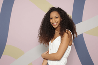 A girl wearing white top with colorful background posing for a picture in a photobooth