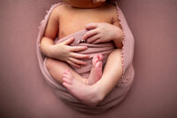 Detail shots of newborn babies hands and toes wrapped in pink