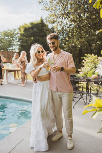 "Couple joyfully cheering with their glasses raised during a wedding toast, surrounded by friends and family in a festive celebration."