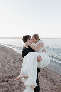 A newlywed holding up their partner as they kiss 