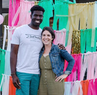 A couple smiling in front of a colorful backdrop, celebrating the moment