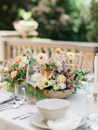 long floral garland sits on a taupe colored linen table that is plated with white dishes and bronze silverware that has fruit crackers and cheese paired with red and white wines at french park in cincinnati by cincinnati wedding florist roots floral design