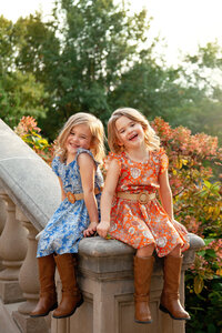 Young twin girls in dresses laughing at University of Iowa campus.
