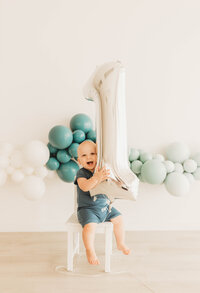 studio session for one year old boy's birthday with blue balloons