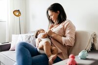 A woman holds and breastfeeds her baby.