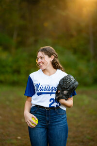 High school senior girl in a softball jersey with glove.