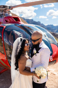 Bride and groom posing in front of helicopter at the grand canyon.