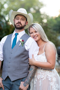 An Austin wedding photographer captures a bride and groom posing for a photo in a cowboy hat.