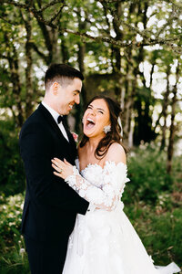 Groom holding his laughing bride with trees in the background at Castle Dargan, Sligo