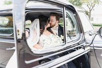 Detroit wedding couple kissing inside a vintage Motor City car, bride holding white bouquet, romantic fall wedding photography