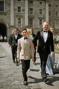 Two grooms walking outside of Trinity College for their LGBTQ+ wedding in Dublin, Ireland