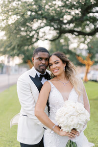 Groom embraces his bride outside on their wedding day